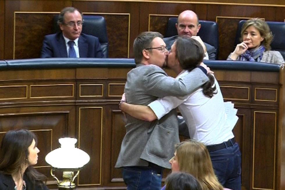 El líder de Podemos, Pablo Iglesias, y el de En Comú Podem, Xavier Domènech, se besan en el Congreso durante la segunda jornada del debate de investidura del líder socialista.